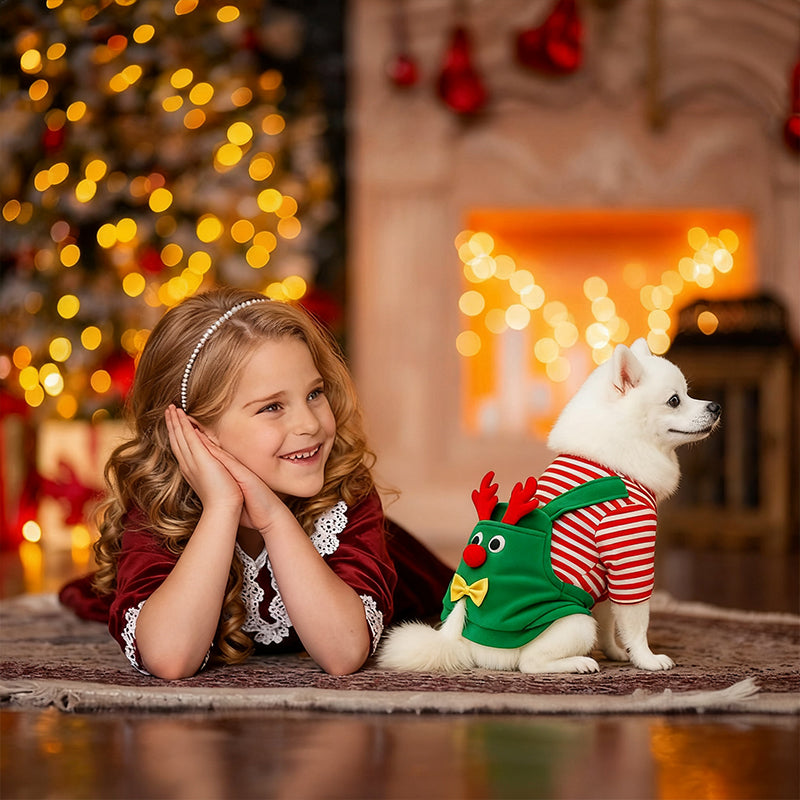 Festive pet apparel: dog in green reindeer costume with red striped shirt and yellow bow beside a smiling girl